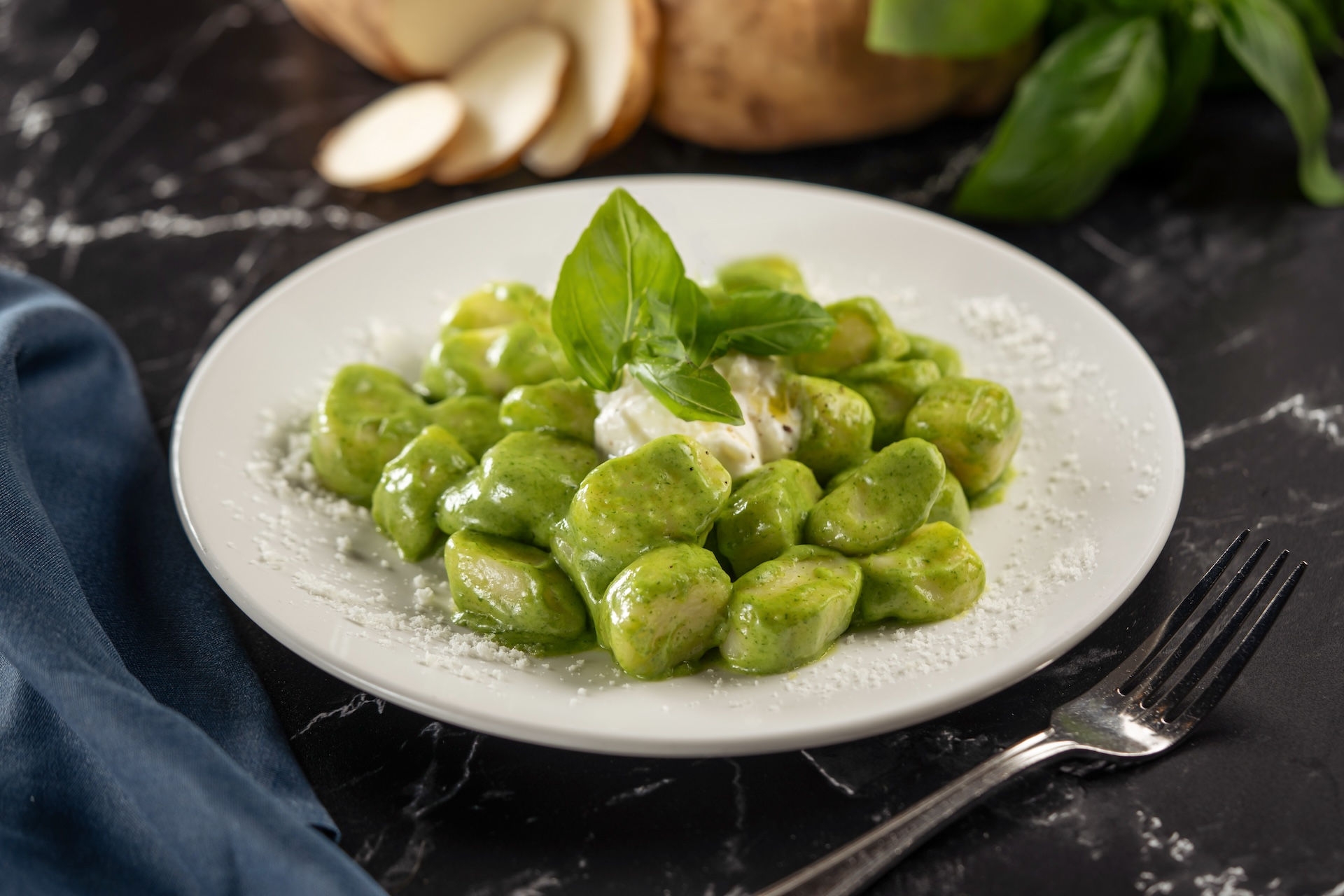 Gnocchi in a green sauce with burrata cheese, garnished with basil leaves.