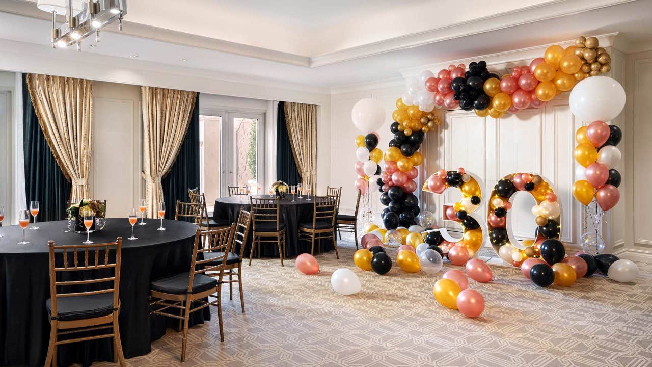 A decorated room with a "50" balloon display, black-covered tables, and chairs set for an event or celebration.