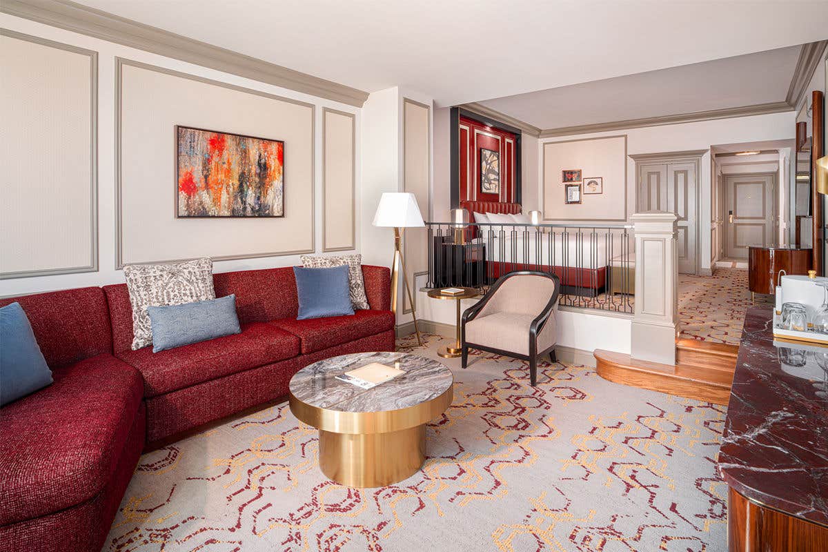 A suite in The Venetian South Tower showing the step down living area with a red seating area and table, with the bed in the background