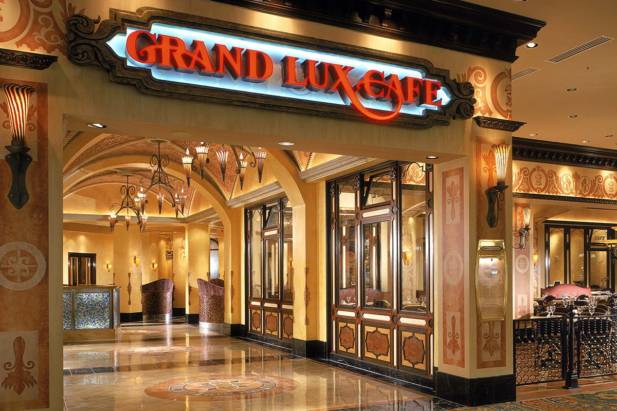 Grand Lux Café entrance with ornate lighting, decorative archways, and luxurious interior visible through large windows.