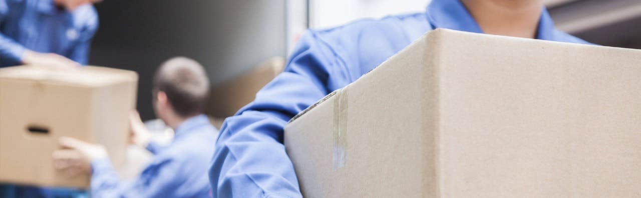 Workers in blue uniforms moving brown cardboard boxes.