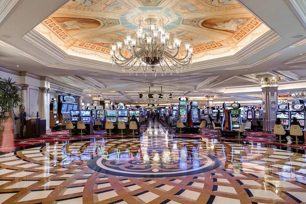 Large open area in the casino near the slot machines with a hanging chandelier and intricate floor pattern.