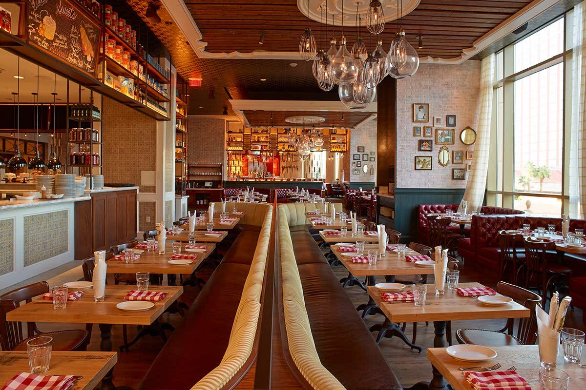 Cozy restaurant with a warm ambiance, featuring wooden tables, red checkered napkins, and hanging glass light fixtures.