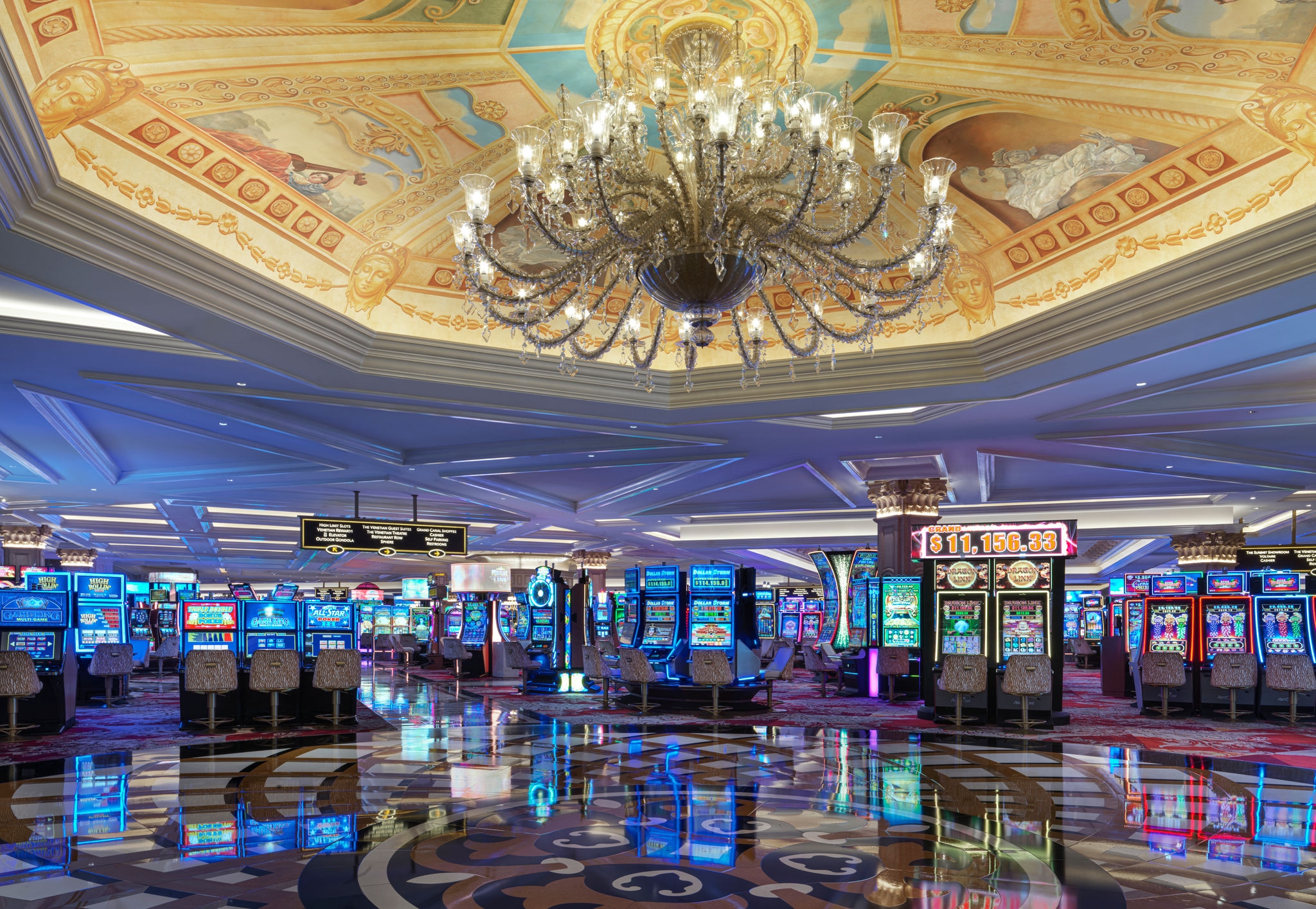 Large open area in the casino near the slot machines with a hanging chandelier and intricate floor pattern.