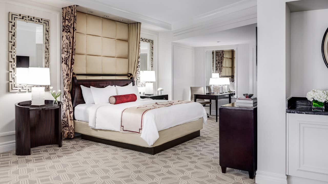 Luxurious hotel room with a large bed, modern furniture, and elegant decor in neutral tones.