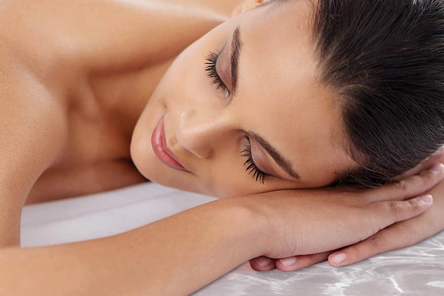 Woman lying with her eyes closed, head resting on her crossed arms, appearing relaxed and serene.