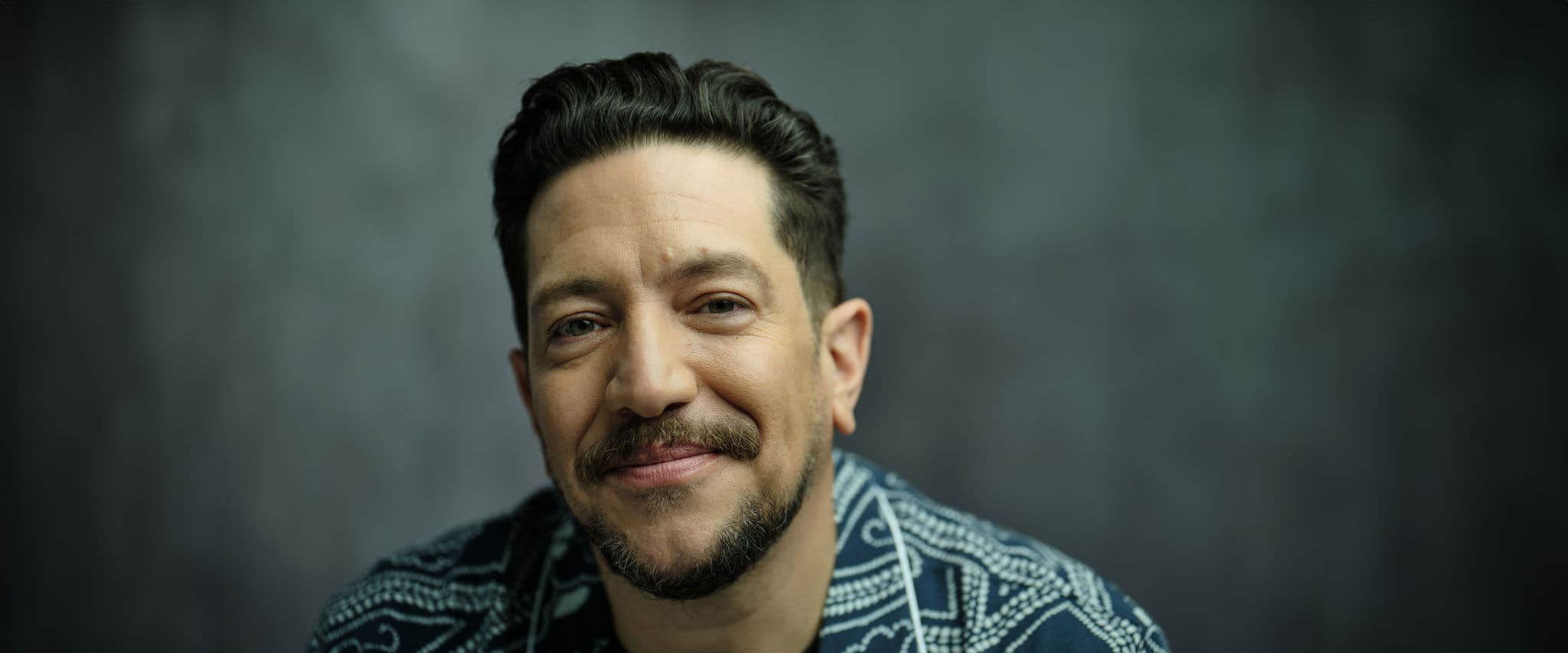 A headshot of Sal Vulcano against a dark blue backdrop