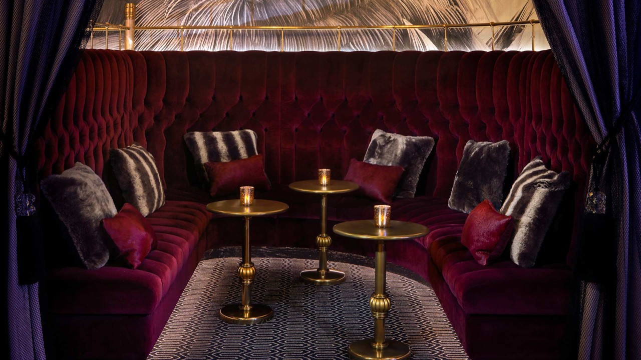 Luxurious private lounge with plush velvet seating, metallic tables, ambient lighting, and chic pillows.