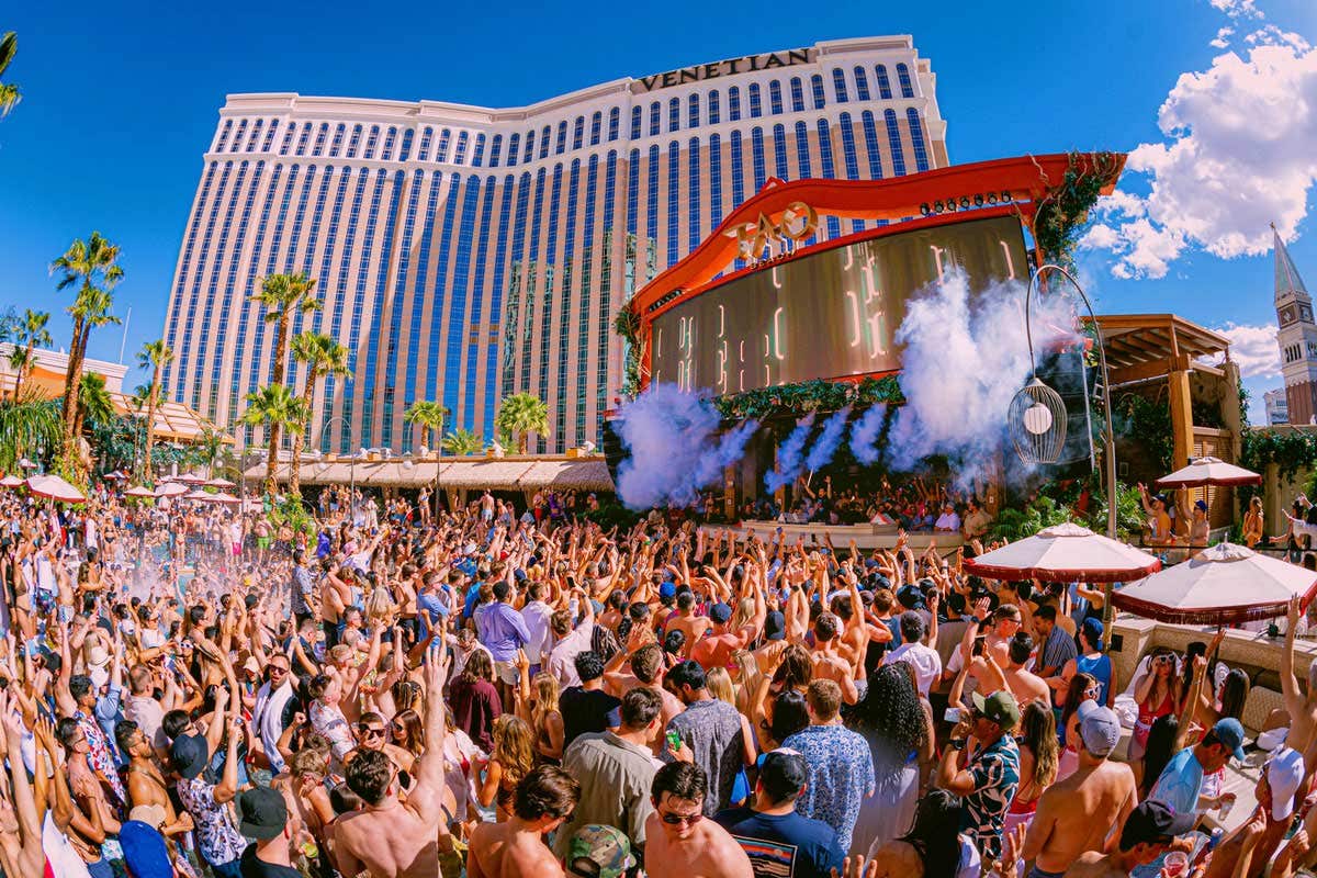 A large crowd at TAO Beach in front of the main stage with The Venetian Resort in the background