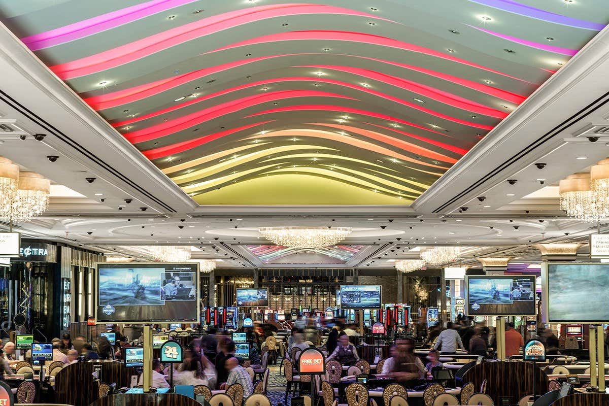 Interior of casino, bright lights, people playing games