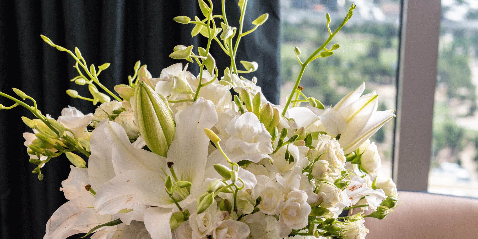 A close-up of a white floral bouquet with lilies and roses.