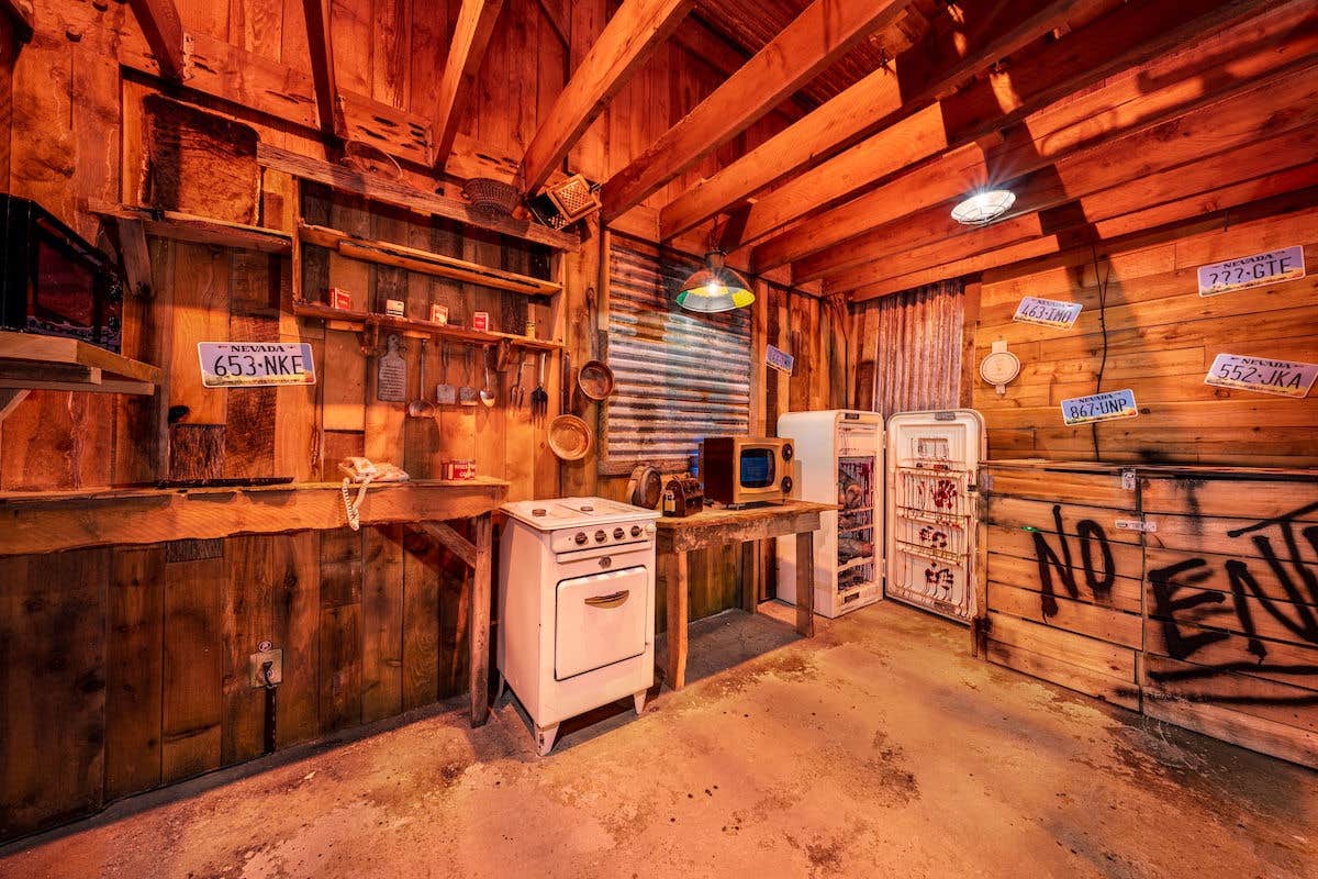 An abandoned cabin with bloodstained old appliances and license plates on the walls.