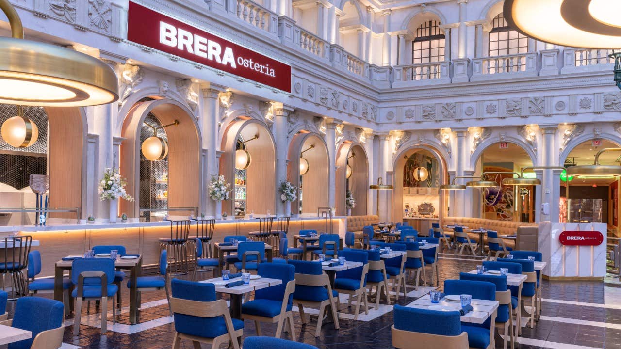 Elegant, modern restaurant with blue chairs, white tables, and arched windows, labeled "Brera Osteria.