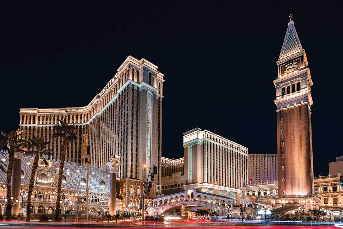 Night view of The Venetian resort in Las Vegas, showcasing its illuminated architecture and palm trees.