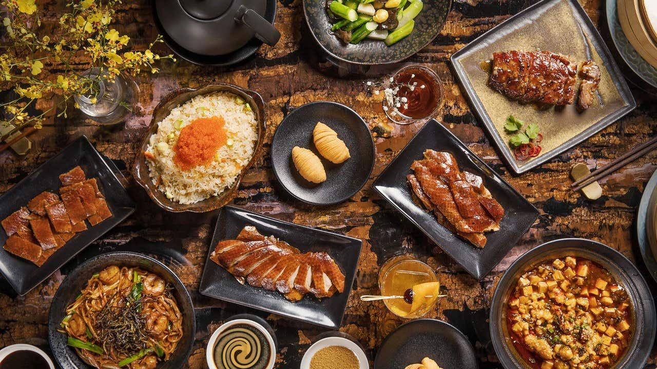 A table filled with various Asian dishes, including rice, meats, noodles, vegetables, soups, and several small side dishes.