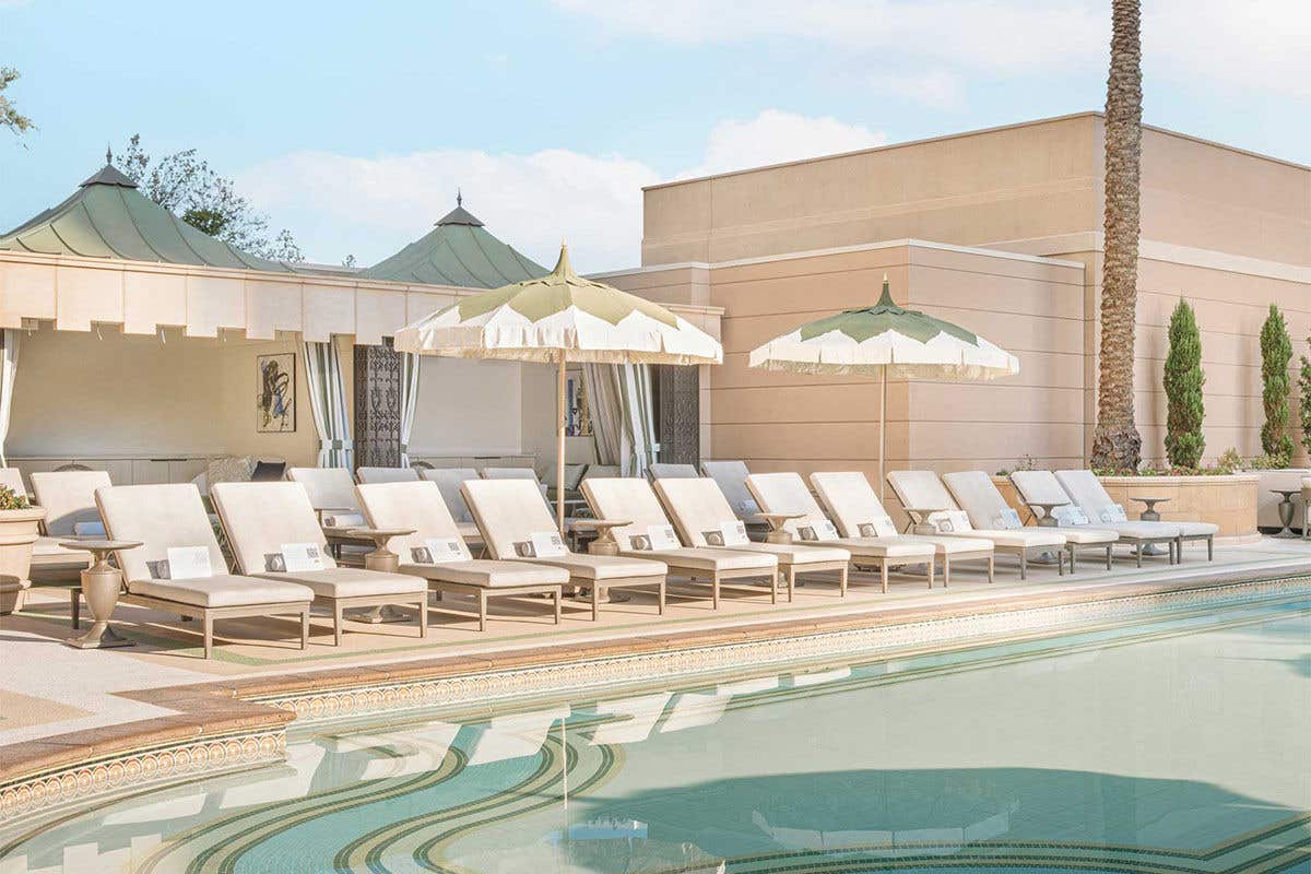 A pool with lounge chairs and a building in the background.