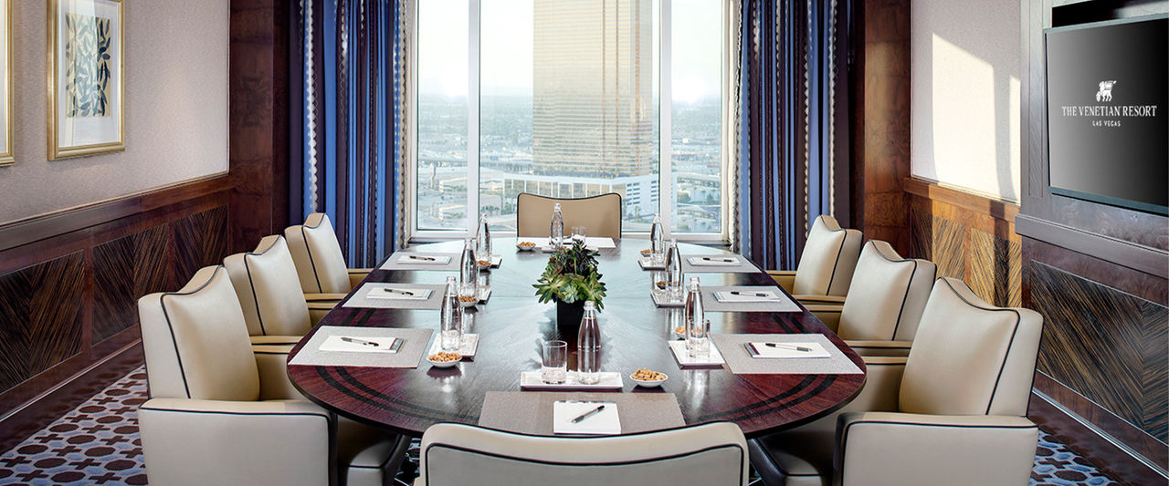 An oval table with 8 chairs in a bright room with a view of Las Vegas